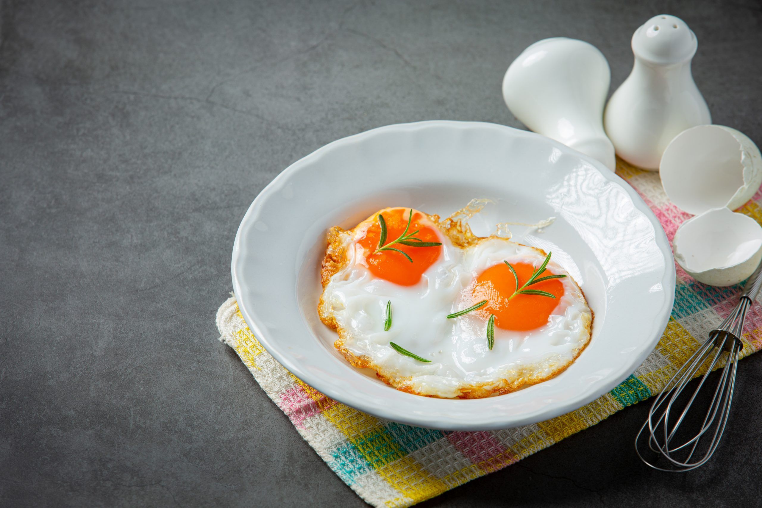 Fried eggs in a white plate on dark background
